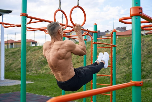 Кавказский мужчина без рубашки делает тренировку брюшного пресса на открытом воздухе