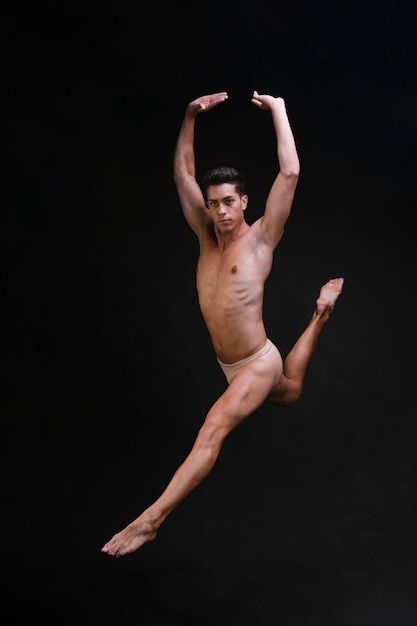 Танцор без рубашки прыгает с поднятыми руками