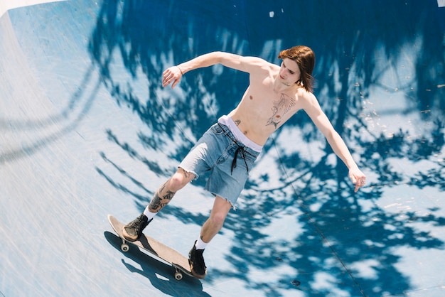 Shirtless extreme man riding skateboard