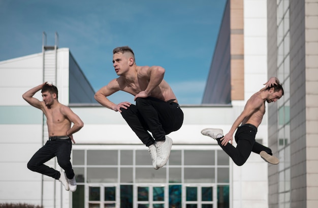 Shirtless male hip hop artists posing mid-air