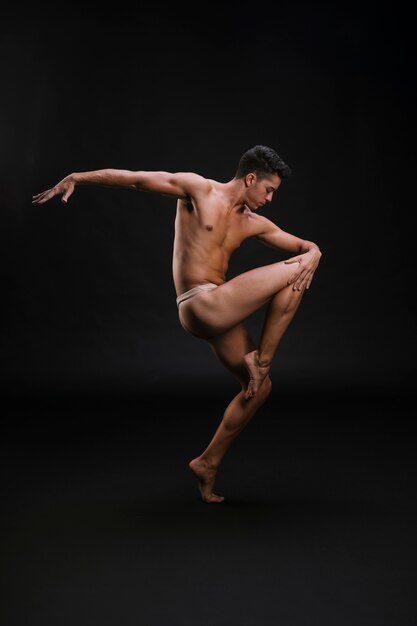 Shirtless man dancing on tiptoes