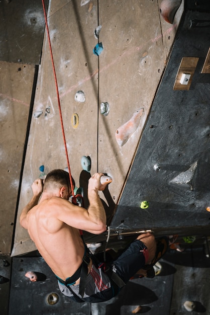 Shirtless man hanging on ledge