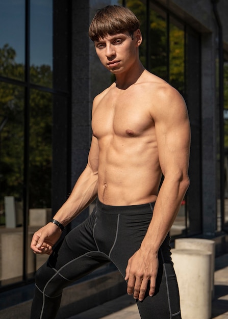 Free photo shirtless man posing outdoors while exercising