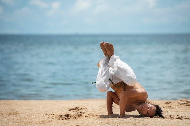 Shirtless man practicing capoeira by himself on the beach