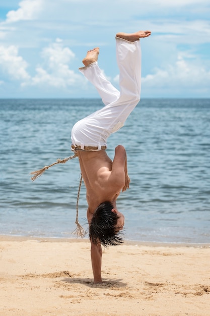 Free photo shirtless man practicing capoeira by himself on the beach