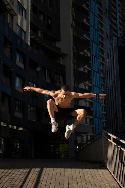 Бесплатное фото Мужчина без рубашки занимается паркуром на открытом воздухе