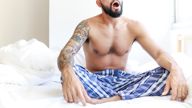 Free photo shirtless man sitting on bed