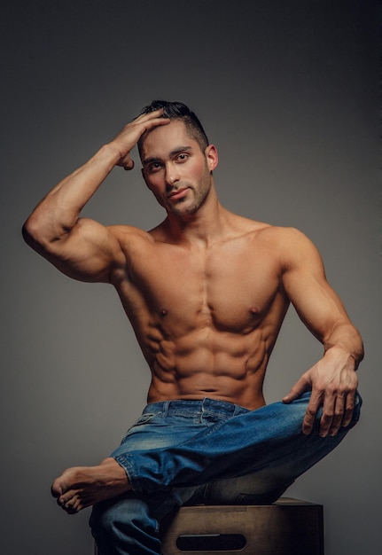 Shirtless muscular man in denim jeans. Isolated on grey background.