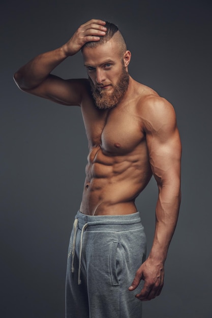 Shirtless muscular man with beard isolated on grey background.