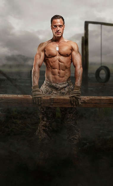 Бесплатное фото Солдат без рубашки с деревянным брусом в болоте.