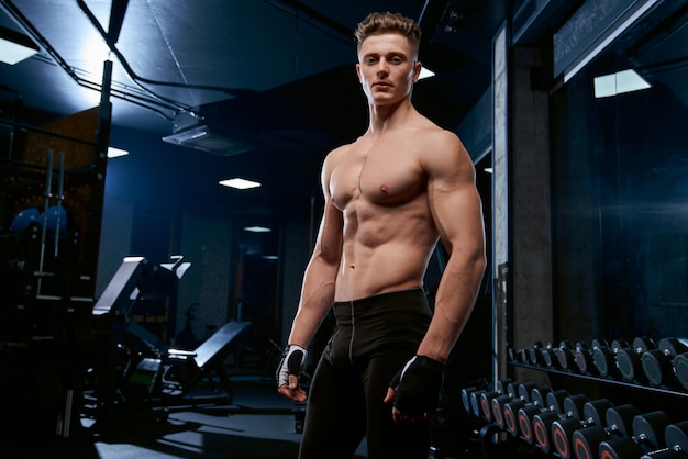 Shirtless sportsman posing in gym.