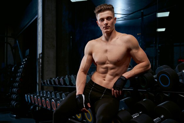 Shirtless sportsman posing in gym.