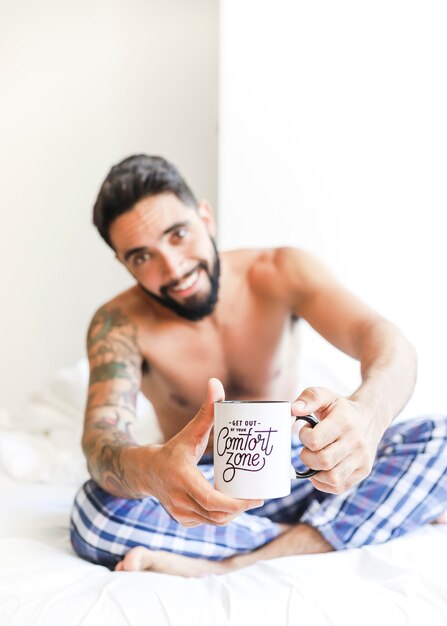 Shirtless young man holding cup of coffee
