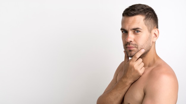 Shirtless young man posing against white background