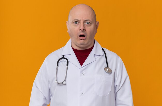 Shocked adult slavic man in doctor uniform with stethoscope looking at front