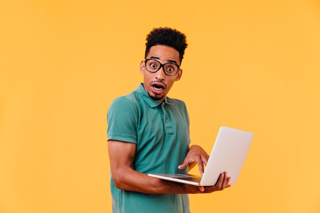 Shocked african student posing while doing homework. disappointed brunette web-developer.