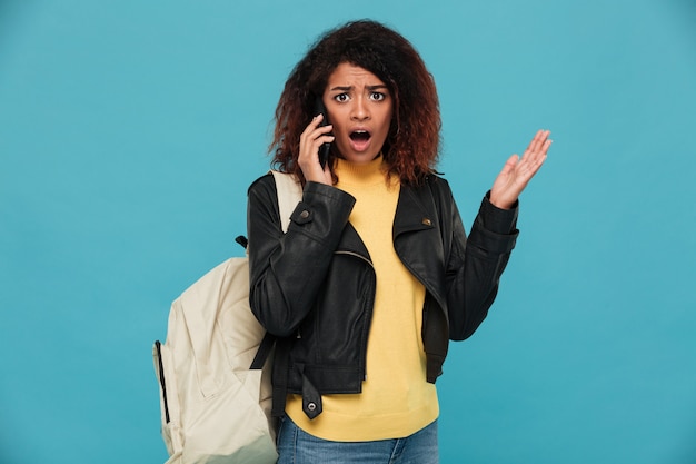 Shocked african woman in leather jacket with backpack