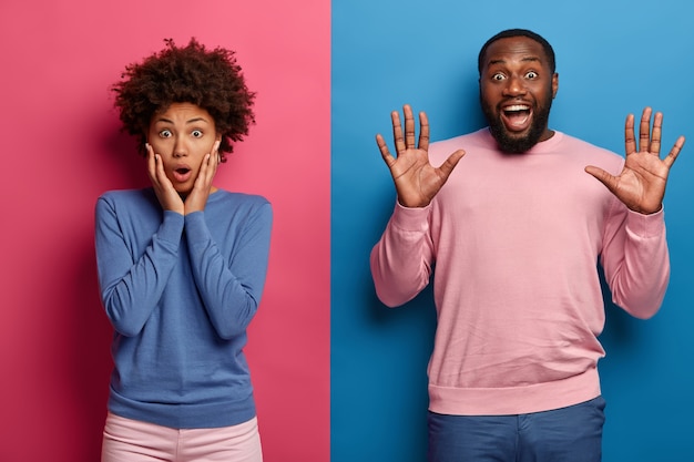 Free photo shocked afro woman keeps hands on cheeks and stares at camera with surprisement