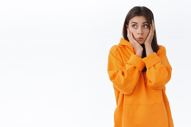 Shocked and amazed caucasian girl hear incredible news process information gossiping and looking left astonished grab head cant believe something happened stand impressed white background