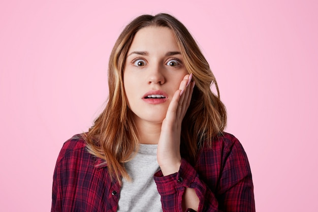 Shocked amazed female looks with eyes full of disbelief at camera