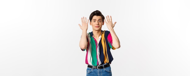 Shocked and annoyed young man shaking hands and looking distressed standing over white background