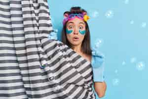 Free photo shocked asian woman surprised as someone came in bathroom while she was taking shower hides her naked body undergoes beauty treatments makes hairstyle poses indoor soap bubbles around. hygiene concept