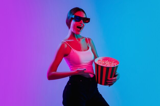 Shocked, astonished. Young caucasian woman's portrait on gradient blue-purple studio background in neon light. Concept of youth, human emotions, facial expression, sales, ad. Beautiful brunette model.