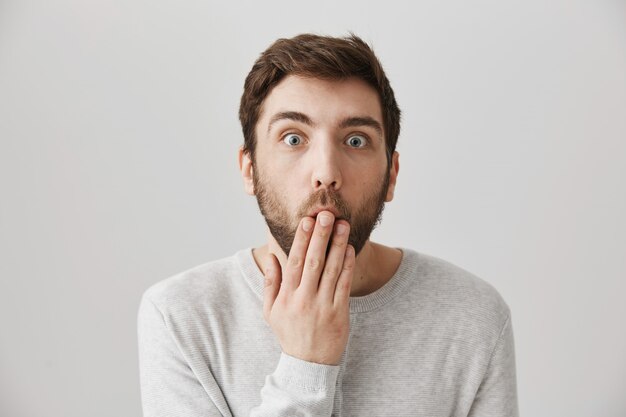 Shocked bearded man cover mouth as hear amazing rumor