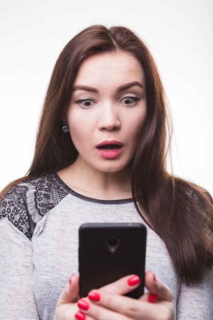 Shocked beautiful young woman looking at mobile phone