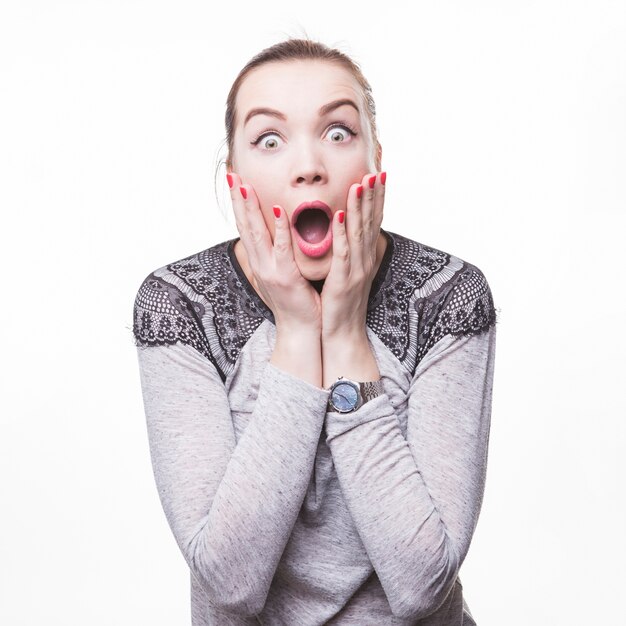 Shocked beautiful young woman with mouth open on white backdrop