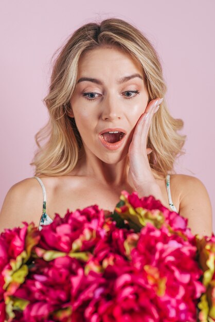 Shocked blonde young woman looking at flower bouquet