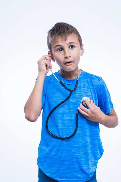 Shocked boy listening to his heartbeat with stethoscope on white background