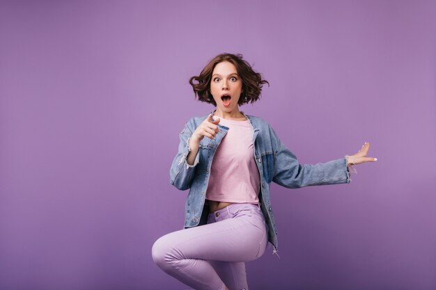 Shocked brown-eyes woman jumping. Joyful short-haired girl in jacket dancing.