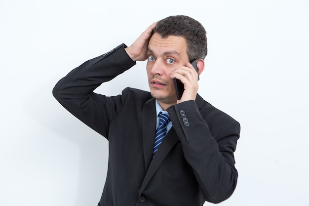 Uomo d'affari shocked che parla sul telefono mobile