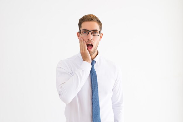 Shocked business man touching cheek with his mouth open