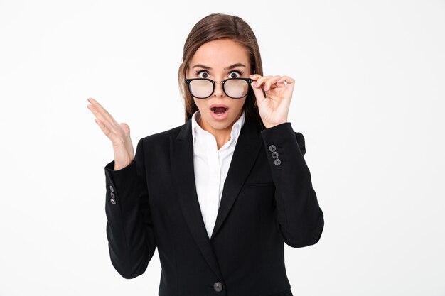 Shocked business woman wearing glasses standing isolated