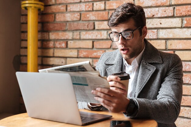 Shocked businessman in eyeglasses sitting by table