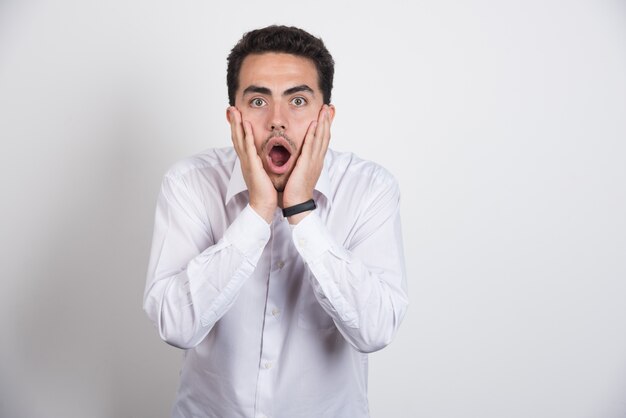 Shocked businessman holding his face on white background.