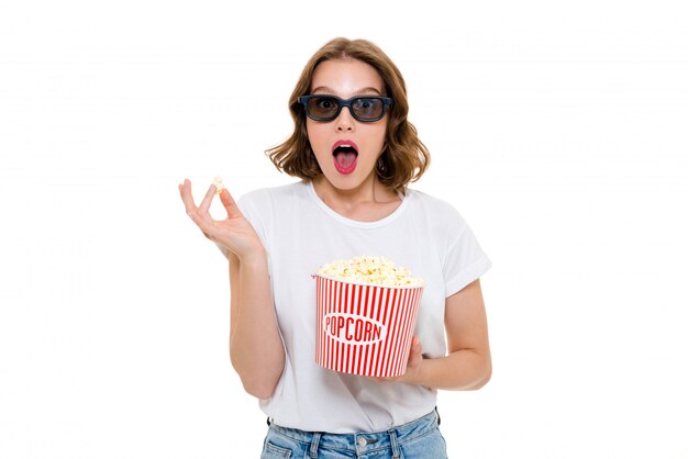 Shocked caucasian woman holding pop corn wearing 3d glasses