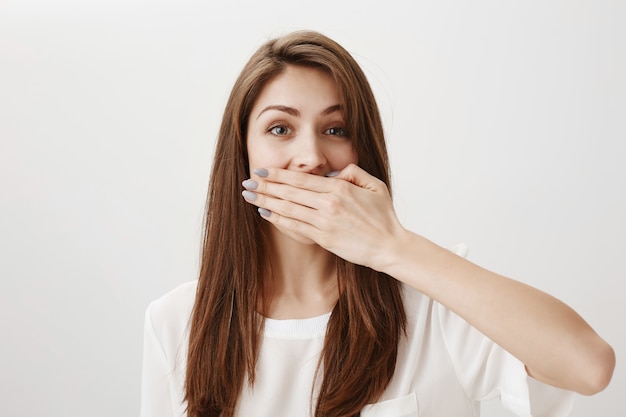 Shocked cheerful girl cover mouth with palm, stop herself from talking
