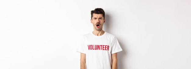 Free photo shocked and confused man in volunteer tshirt staring at camera and frowning displeased standing agai