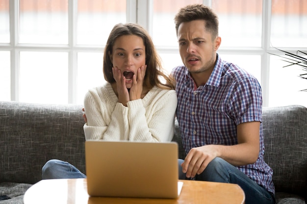 Shocked couple confused and scared watching horror movie on laptop