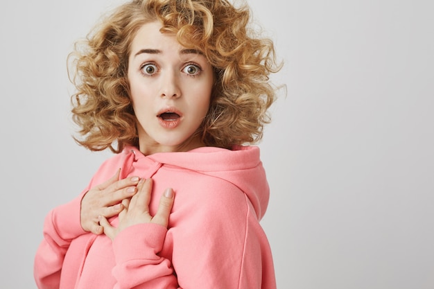 Shocked curly-haired woman gasping amazed, looking startled