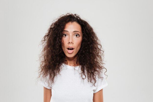 Shocked curly woman looking at the camera