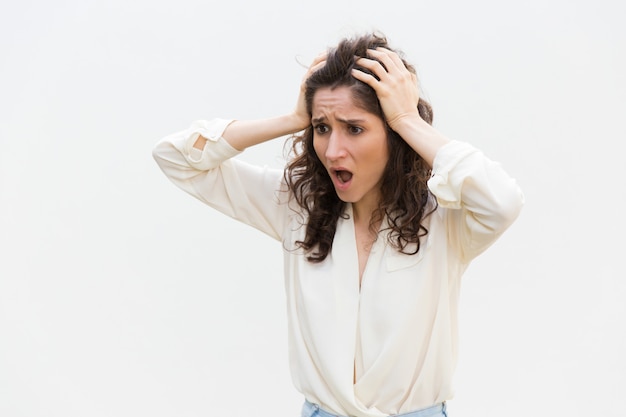 Shocked disappointed woman gasping, holding head