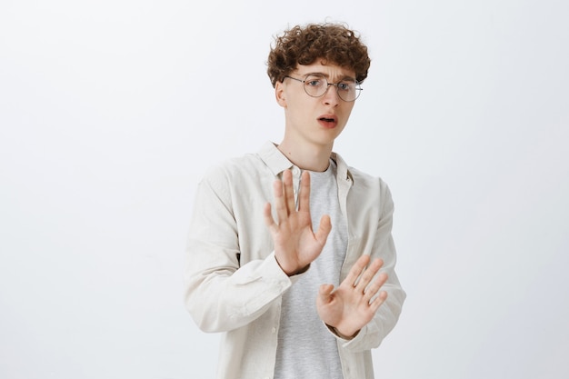 Shocked and disgusted teenage guy posing against the white wall