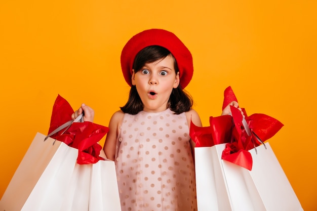 Shocked european child posing after shopping. kid holding store bags with mouth open