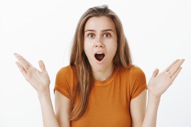 Shocked and excited blond girl drop jaw and raise hands up, see something unbelievable