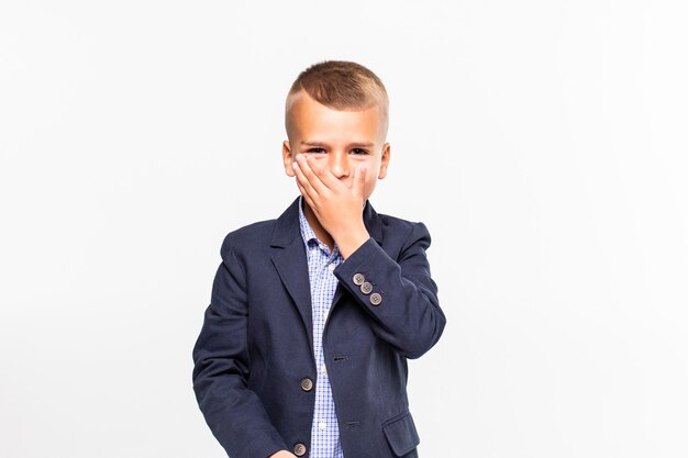 A shocked frightened young boy covering his mouth with his hand isolated on white.