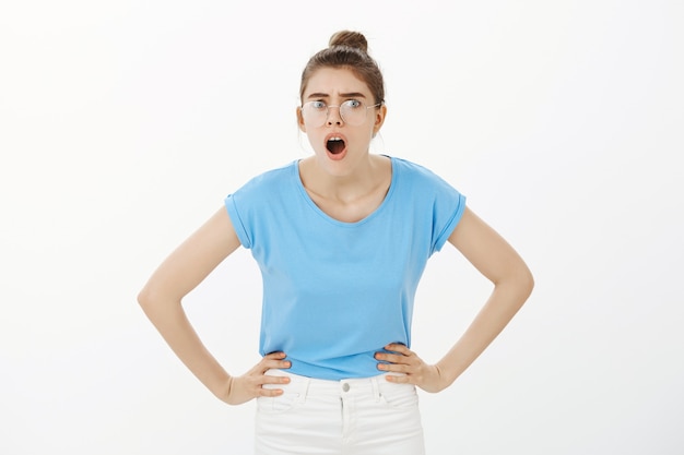 Shocked and frustrated woman in glasses gasping, looking closer to something upsetting